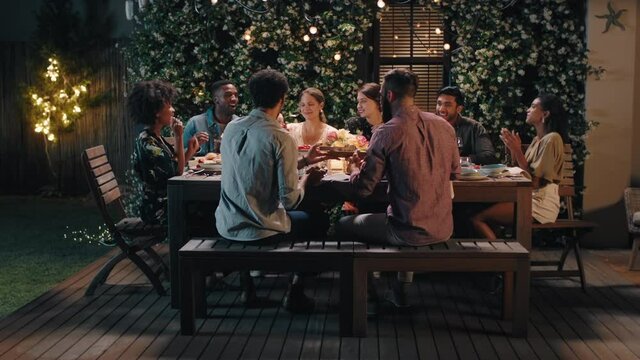 dinner party friends celebrating evening together sharing homemade meal enjoying casual conversation having fun weekend reunion relaxing on calm summer night outdoors 4k footage