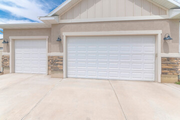 Exterior of a garage with white double sectional doors and wall mounted lighting fixtures