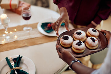 Close-up of African American couple eats donuts for dessert on Christmas at home.