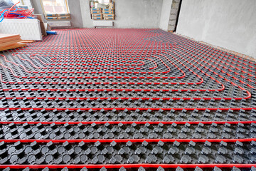 Installation of a heat flooring system in a country house under construction. Red tubes for floor...