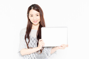 Fototapeta premium 小さいスケッチブックを持って案内をするカジュアルな服を着ている女性