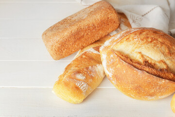 Assortment of fresh bread on white wooden background