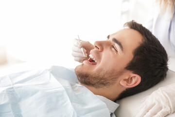 Dentist examining teeth of young man in clinic
