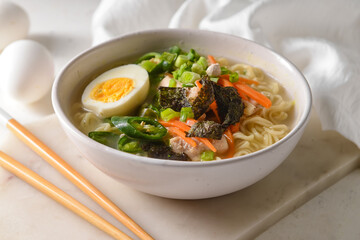 Tasty Chinese soup with chicken in bowl on light background