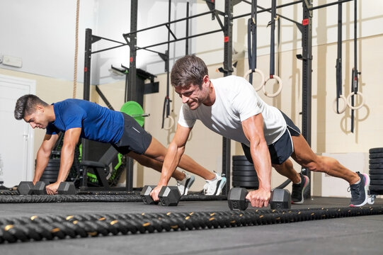 Two strong men doing push-ups in gym. High quality photo.