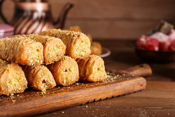 Board with delicious baklava on wooden background, closeup