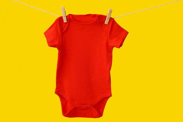 Baby clothes hanging on rope against color background