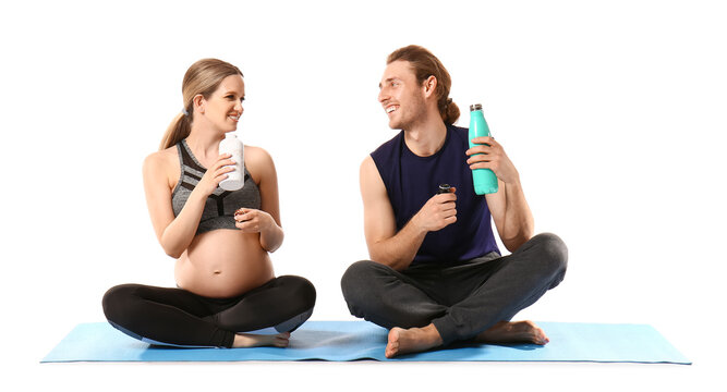 Young pregnant woman and her husband practicing yoga on white background