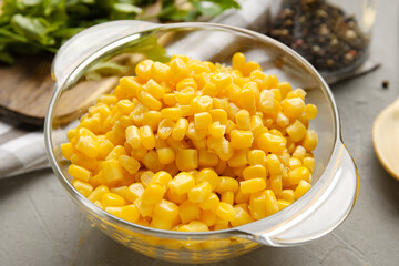 Bowl with corn kernels on grey background, closeup