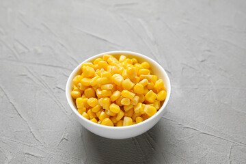 Bowl with corn kernels on grey background