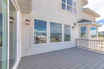 Deck of a house with sliding glass windows and open wall lamps