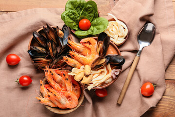 Bowl of tasty Cacciucco soup and ingredients on wooden background