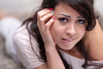 Thoughtful troubled young woman biting her lip