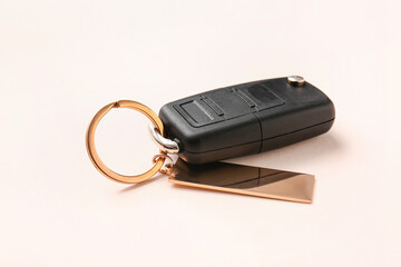 Car key with stylish keychain on light background, closeup