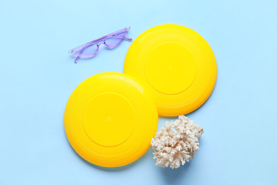 Frisbee disks, sunglasses and coral on color background