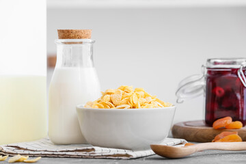 Bowl with tasty corn flakes and bottle of milk on table in kitchen