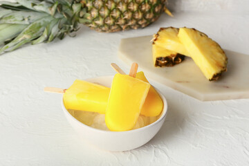 Bowl with tasty pineapple popsicles on light background