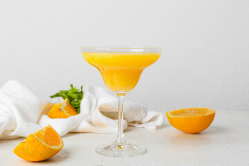 Glass of orange margarita cocktail on light background