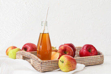 Bottle of apple juice and fresh fruits on light background