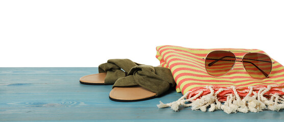 Beach towel, slippers and sunglasses on light blue wooden surface against white background. Space for text
