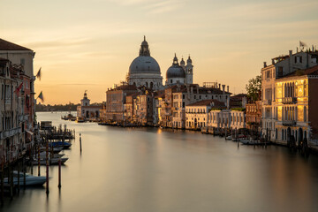 Fototapeta na wymiar Venice, Italy. Sunrise view of the Grand Canal and Basilica Santa Maria della Salute. Focus on basilica, boats slightly blurred by long exposure.