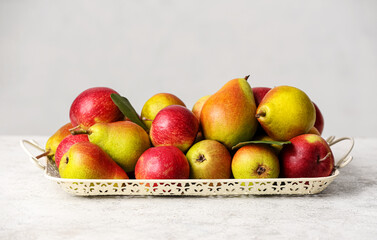 Tray with ripe pears and apples on light background