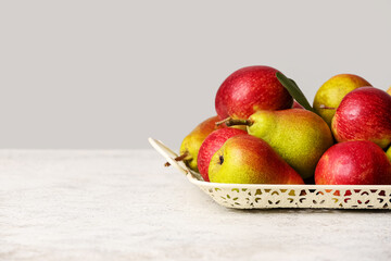 Tray with ripe pears and apples on light background, closeup