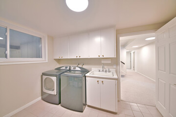 Interior of a laundry room with an open white door and a view of the hallway