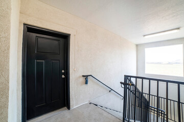 Black front door of an apartment unit beside the stairwell