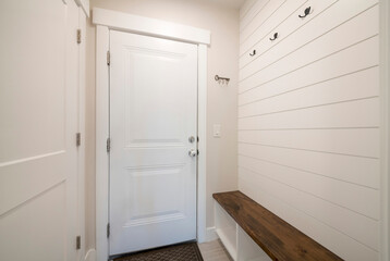 Mudroom interior with white door to the garage and wood panel interior