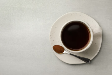 Cup of delicious chicory drink and spoon with powder on light grey table, top view. Space for text