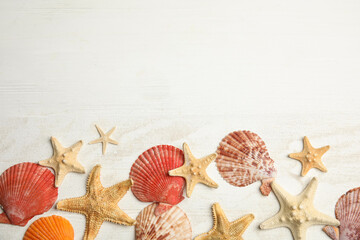 Fototapeta na wymiar Beautiful sea stars, shells and sand on white wooden background, flat lay. Space for text