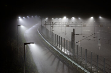 Foggy night and lights with fenced in railway lines in Norway