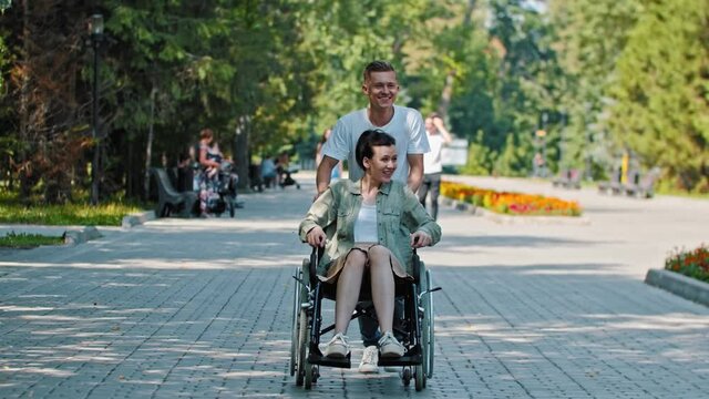 Friends walking in park - a woman in a wheelchair and her friend fooling around
