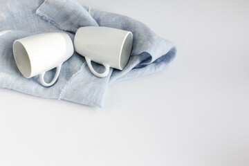 Obraz premium Dishes for a couple. Two porcelain cups for double espresso lie on a linen towel and dry after washing.