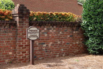Private property towing enforced wood sign against a brick wall with a shallow depth of field and...
