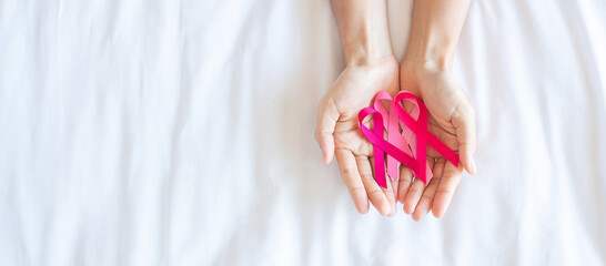 Obraz na płótnie Canvas October Breast Cancer Awareness month, adult Woman hand holding Pink Ribbon on pink background for supporting people living and illness. International Women, Mother and World cancer day concept