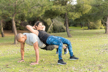 Fitness couple doing back to back lifting exercise in the park