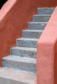 Closeup Of Weathered Concrete Stairs With Orange Stucco Adobe Walls