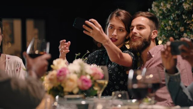 happy couple enjoying dinner party using smartphone taking photos together enjoying reunion with friends sharing romantic evening on social media 4k footage