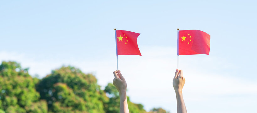 hand holding China flag on blue sky background. National Day of the People Republic of China, public Nation holiday Day and happy celebration concepts
