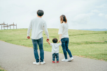 手を繋いで歩く家族（後ろ姿）
