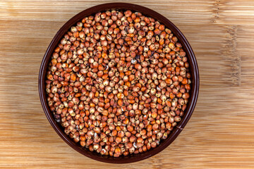 red sorghum (Sorghum bicolor) seeds on a wooden background. Photo produced in a studio