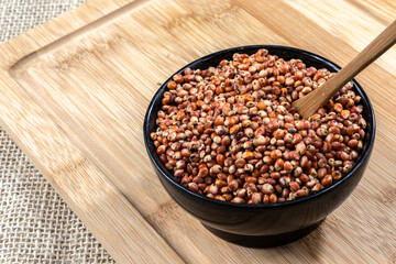 red sorghum (Sorghum bicolor) seeds on a wooden background. Photo produced in a studio