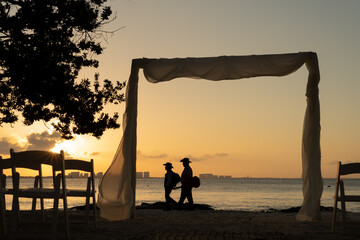 Destination wedding stage in Cancun at sunset with two mariachis walking on empty beach due to pandemic