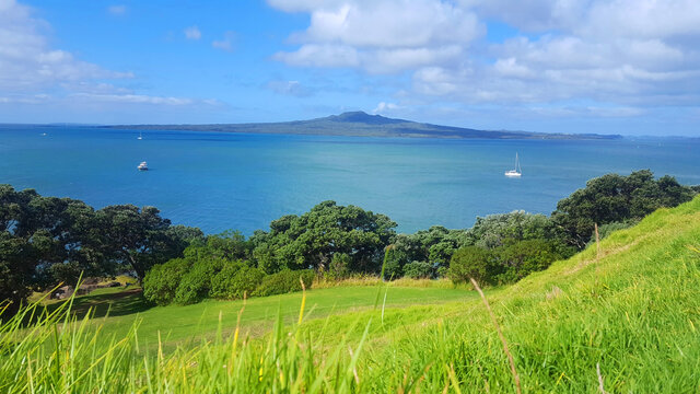 View on Rangitoto island from the grass field of  North head reserve hill with ocean and boats 