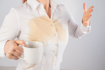 Fototapeta na wymiar Clumsy business woman spills a cup of black coffee on her blouse.
