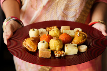 Indian woman serve Diwali sweets Gujiya peda barfi Indian Sweet dessert mithai festival dish...