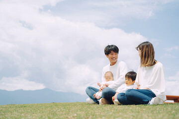 空と芝生に座る家族・ファミリー（4人）
