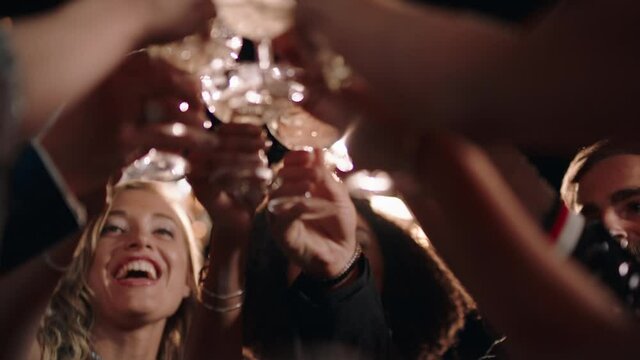 group of stylish friends celebrating at glamorous rooftop party event making toast drinking champagne at formal social gathering enjoying evening celebration at night 4k